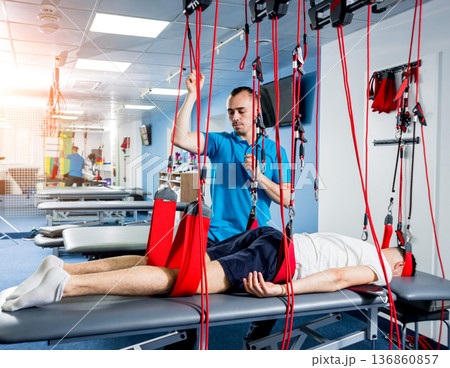 Physiotherapy. Suspension training therapy. Young man doing fitness traction 136860857