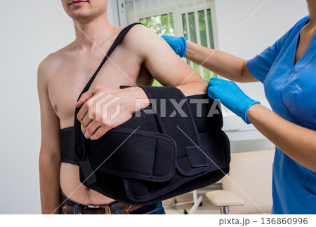 Nurse putting a sling on patients arm that is broken. Injury 136860996