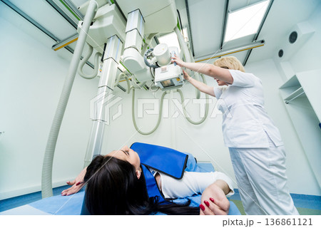 Radiologist and patient in a x-ray room. Classic ceiling-mounted x-ray system. 136861121