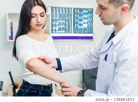 Traumatologist examining patient hands in modern hospital Traumatologist examining patient hands in modern hospital 136861653