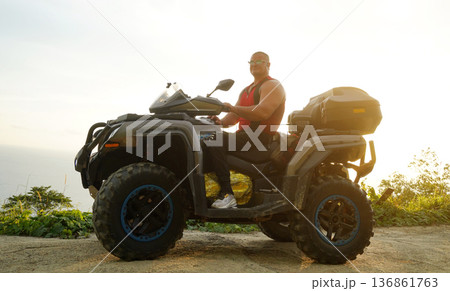 A man engages in extreme ATV riding on mountains in the evening 136861763