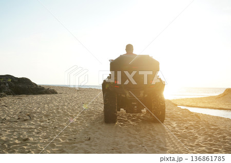 A man engages in extreme ATV riding on sand beach early in the morning A man engages in extreme ATV riding on sand beach early in the morning 136861785