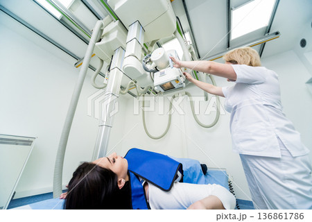 Radiologist and patient in a x-ray room. Classic ceiling-mounted x-ray system. 136861786