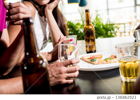 Cheerful friends in the pub. Drinking beer, talking, having fun. 136862021