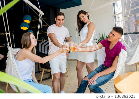 Cheerful friends in the pub. Drinking beer, talking, having fun. 136862023