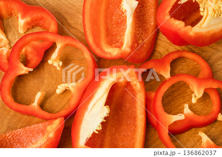 Sliced pieces, parts, lobes of sweet pepper, red, scattered on a wooden board Sliced pieces, parts, lobes of sweet pepper, red, scattered on a wooden board 136862037