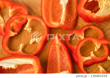 Sliced pieces, parts, lobes of sweet pepper, red, scattered on a wooden board Sliced pieces, parts, lobes of sweet pepper, red, scattered on a wooden board 136862038