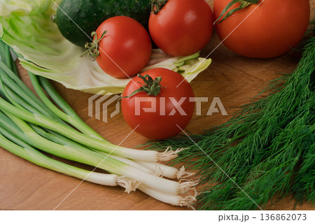 A set of vegetables consisting of tomatoes, cucumbers, parsley, dill and cabbage. On a cutting board A set of vegetables consisting of tomatoes, cucumbers, parsley, dill and cabbage. On a cutting board 136862073