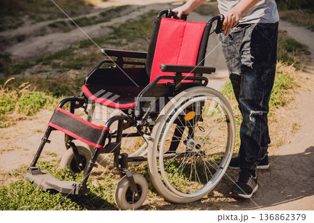 Disabled man resting in a campsite with friends. Wheelchair in the forest  136862379