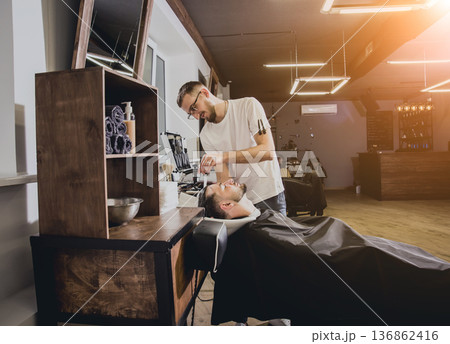 Young man with trendy haircut at barber shop. Barber washes customer head. 136862416