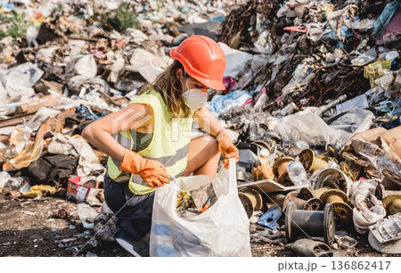 Woman volunteer helps clean the field of plastic garbage. Woman volunteer helps clean the field of plastic garbage. 136862417
