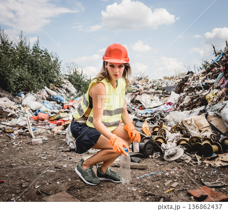 Woman volunteer helps clean the field of plastic garbage. Woman volunteer helps clean the field of plastic garbage. 136862437