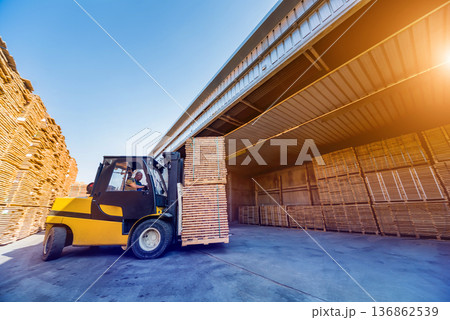 Forklift loader load lumber into a dry kiln. Wood drying in containers. Forklift loader load lumber into a dry kiln. Wood drying in containers. 136862539