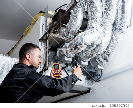Technician use hand-held anemometer measuring air flowing measurement. Technician use hand-held anemometer measuring air flowing measurement. 136862595