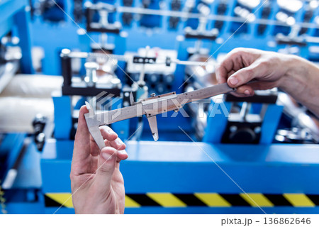 Male hands hold vernier caliper and measure steel collar. 136862646