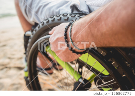 Disabled man in a wheelchair on the beach. Disabled man in a wheelchair on the beach. 136862773
