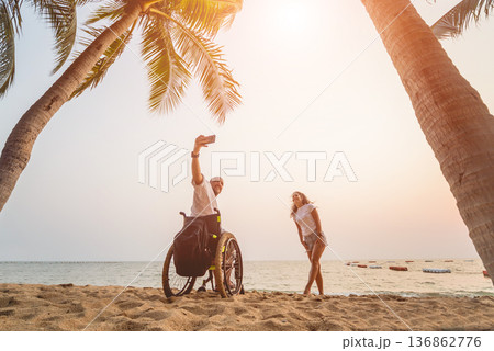 Disabled man in a wheelchair with his wife on the beach. Disabled man in a wheelchair with his wife on the beach. 136862776