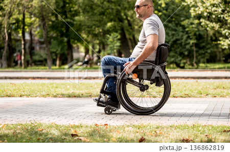 Handicapped man in wheelchair walk at the park alley Handicapped man in wheelchair walk at the park alley 136862819