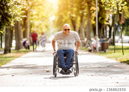 Handicapped man in wheelchair walk at the park alley Handicapped man in wheelchair walk at the park alley 136862830