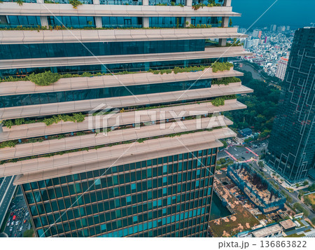 Eco friendly skyscraper with green balconies and modern architecture in Ho Chi Minh City, Sustainable highrise tower with greenery terraces and glass facade in Saigon urban skyline 136863822
