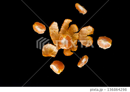 Ripe fruit of the citrus plant mandarin, peeled slices and the peel itself, on a black background Ripe fruit of the citrus plant mandarin, peeled slices and the peel itself, on a black background 136864298