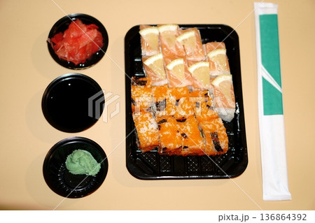 a set of sushi rolls in a plastic container and additional spices in a plastic bowl a set of sushi rolls in a plastic container and additional spices in a plastic bowl 136864392