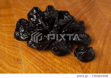 Dried dried prunes in a heap on a wooden board Dried dried prunes in a heap on a wooden board 136864406