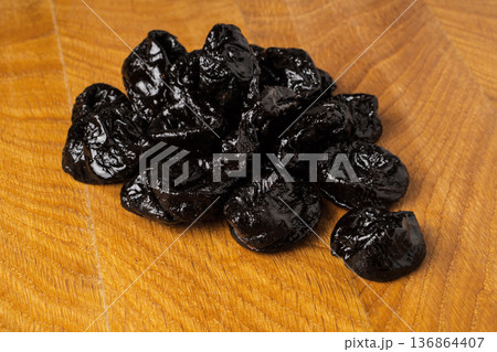 Dried dried prunes in a heap on a wooden board 136864407