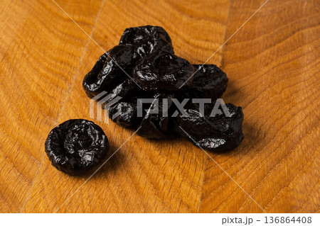 Dried dried prunes in a heap on a wooden board 136864408