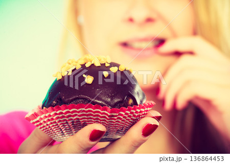 Cute blonde woman thinking about eating cupcake Cute blonde woman thinking about eating cupcake 136864453