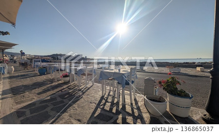 Tables on the sidewalk along the coast under the sun and blue sky Tables on the sidewalk along the coast under the sun and blue sky 136865037