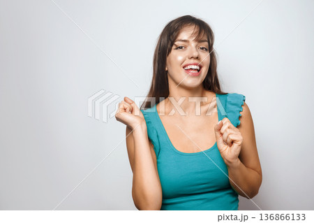 Smiling woman in blue outfit dances happily in front of a plain wall Smiling woman in blue outfit dances happily in front of a plain wall 136866133