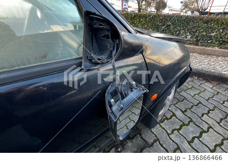 Broken car side mirror hanging from black vehicle door with exposed wires after accident damage close up outdoors. Broken car side mirror hanging from black vehicle door with exposed wires after accident damage close up outdoors. 136866466