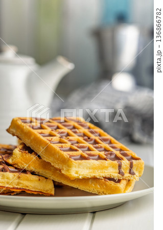 Sweet waffles with chocolate on plate on kitchen table. 136866782