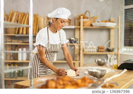 Elderly woman kneads dough in bakery Elderly woman kneads dough in bakery 136867396