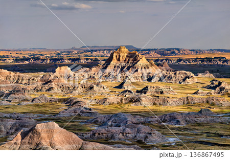 Scenic landscape view of distant rugged rock formations and prairie seen from Cliff Shelf Trail at Badlands National Park, South Dakota, United States. 136867495