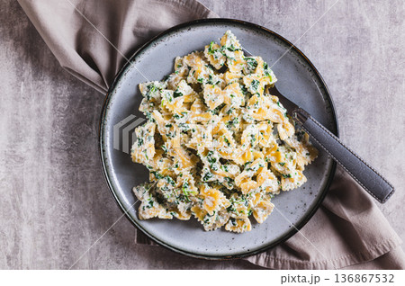 Close up of appetizing farfalle with ricotta and spinach on a plate on the table top view Close up of appetizing farfalle with ricotta and spinach on a plate on the table top view 136867532
