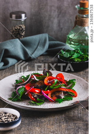 Warm salad with fried eggplant, bell pepper, onion, and herbs on a plate on the table vertical view Warm salad with fried eggplant, bell pepper, onion, and herbs on a plate on the table vertical view 136867538