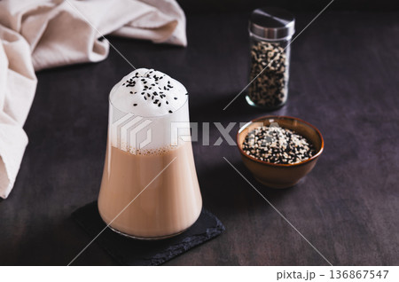Black sesame coffee with a fluffy creamy foam in a glass on the table 136867547