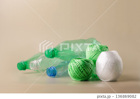 Plastic bottles balls of yarn on light background, symbolizing the eco-friendly process of recycling waste into textiles. Sustainable living, plastic recycling, reuse Plastic bottles balls of yarn on light background, symbolizing the eco-friendly process of recycling waste into textiles. Sustainable living, plastic recycling, reuse 136869082