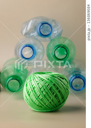 Green yarn ball and plastic bottles representing recycling 136869084