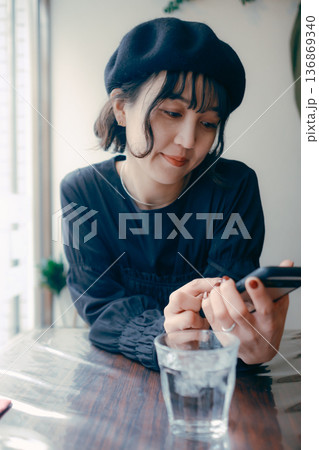 カフェでスマートフォンを見る30代日本人女性 136869340