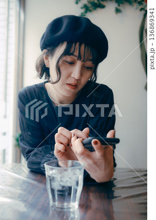 カフェでスマートフォンを見る30代日本人女性 136869341