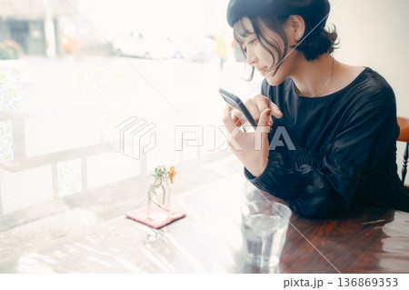 カフェでスマートフォンを見る30代日本人女性 136869353