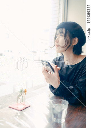 カフェでスマートフォンを見る30代日本人女性 136869355