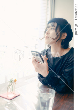 カフェでスマートフォンを見る30代日本人女性 136869356