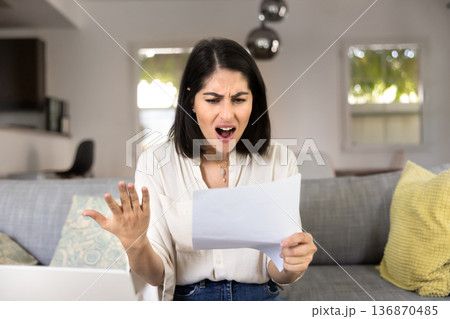 Angry annoyed Latin woman reading formal letter with bad news 136870485