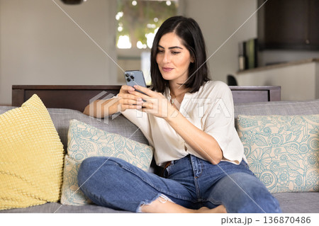 Positive young Latin smartphone user woman texting message Positive young Latin smartphone user woman texting message 136870486