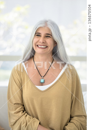 Vertical portrait of overjoyed middle-aged woman posing seated on couch Vertical portrait of overjoyed middle-aged woman posing seated on couch 136870504