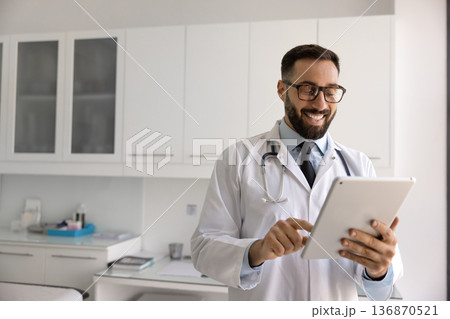 Smiling male doctor giving remote consultation online using digital tablet 136870521
